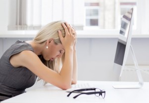 Overworked and tired young woman dealing with stress in front of computer.