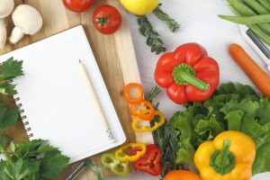 A recipe book surrounded by vegetables.