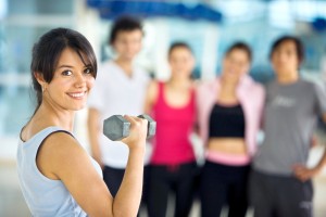 Woman in a gym about to exercise with free weights in front of a group