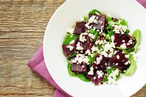 salad with beets spinach and goat cheese on a dark wood background. tinting. selective focus on the middle of the salad